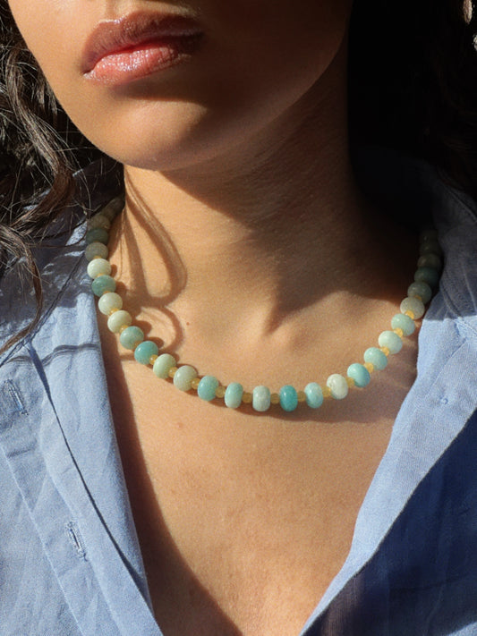try on shot of the hand-beaded Citrine Skies Necklace No.01 in butter yellow agate stones blue stones A soft summer day, captured in stone. Inspired by the golden warmth of citrine sunsets and the tranquility of clear skies. Blends butter yellow and sky blue tones in a dreamy, refreshing palette. Handcrafted with butter yellow natural jade gemstones and finished with 925 sterling silver clasp. -Material: Natural jade stones - Length: 42 cm - 925 sterling silver clasp