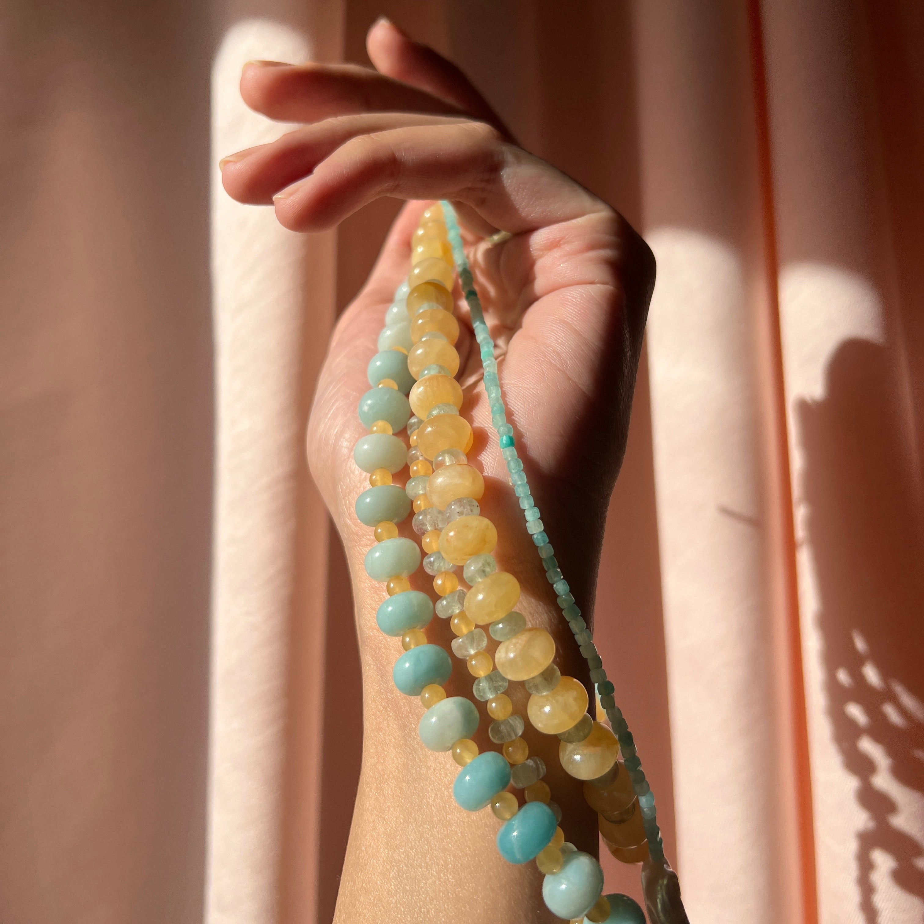 close-up shot of the hand-beaded Citrine Skies Necklace collection in butter yellow agate stones blue stones