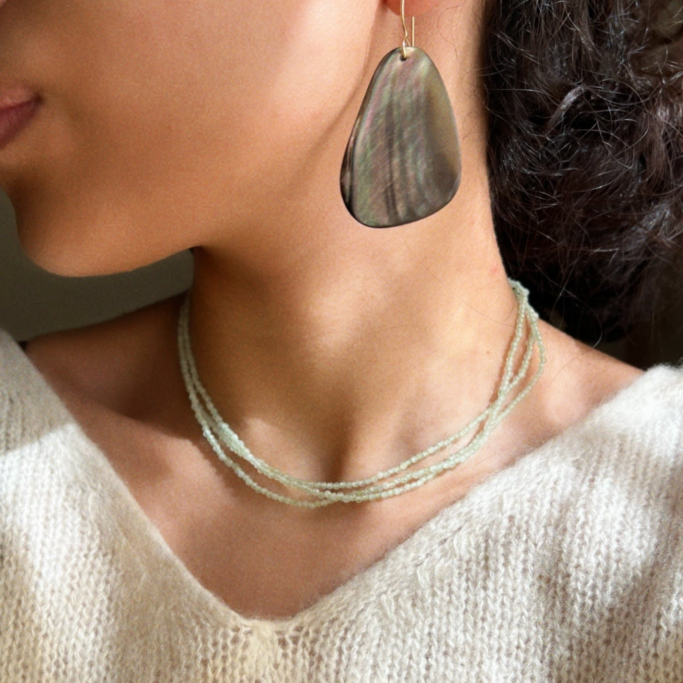 Close-up of shot for mint green three layered necklace and brown shell teardrop earrings.
