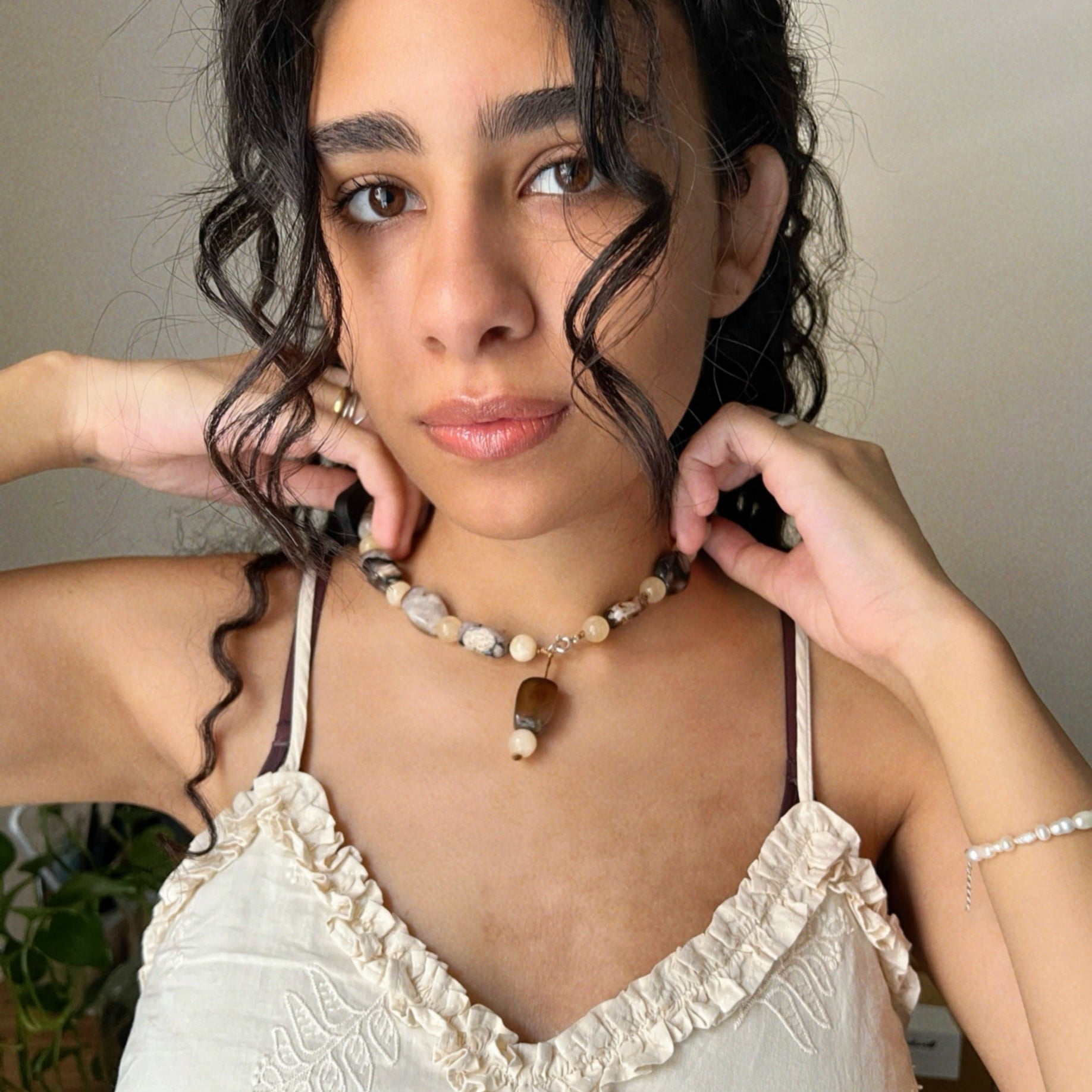 wearing a white lace top and a long necklace made from Madagascar Agate and yellow jade stones