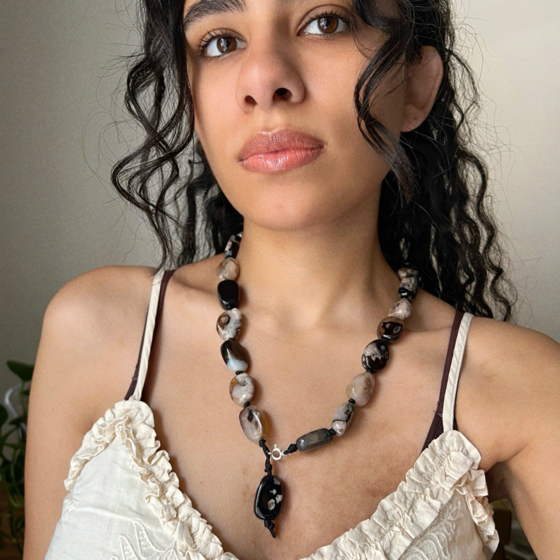 wearing a white lace top and a long necklace made from Madagascar Agate