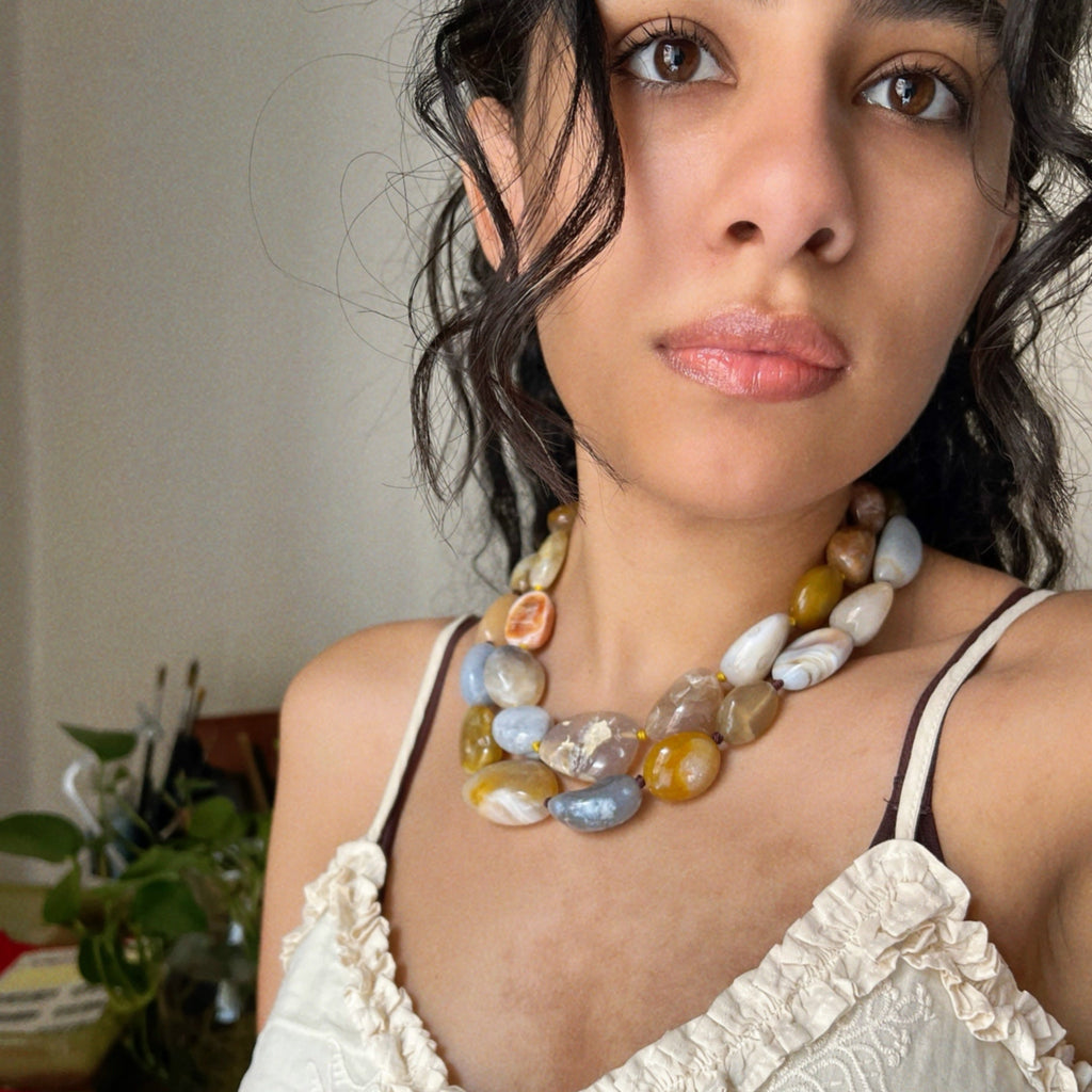 wearing a colorful necklace made from chunky agate stones in oranges and yellow that looks  like wearable mangoes