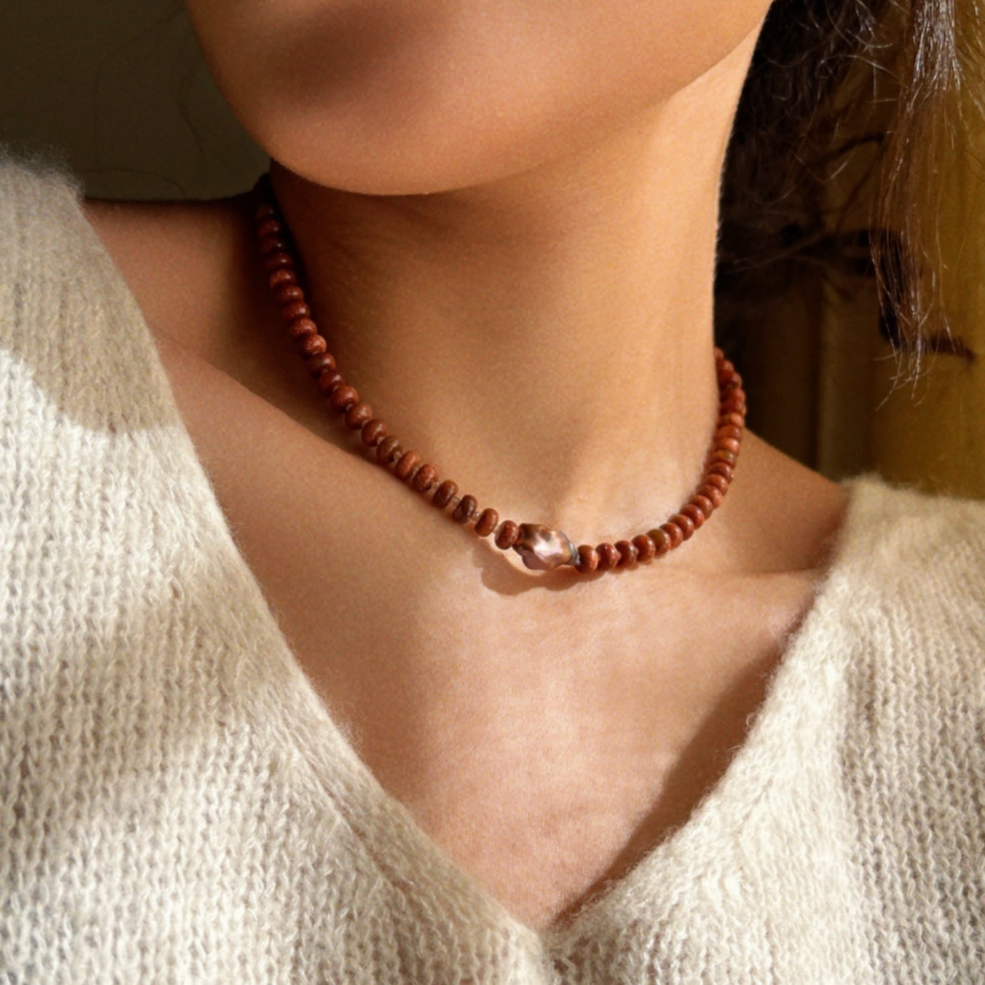 Close-up shot of a brown beaded necklace with a centered brown natural pearl