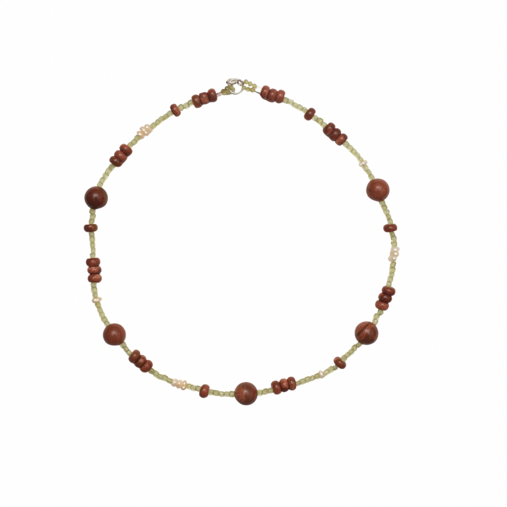 Hand-strung necklace with a mix of round and button shaped golden brown sunstones and green tiny peridot stones on a white background