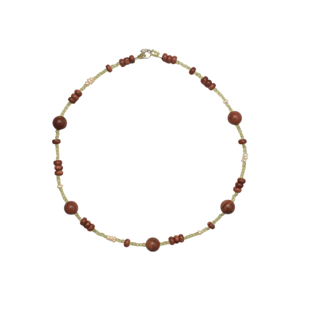 Hand-strung necklace with a mix of round and button shaped golden brown sunstones and green tiny peridot stones on a white background