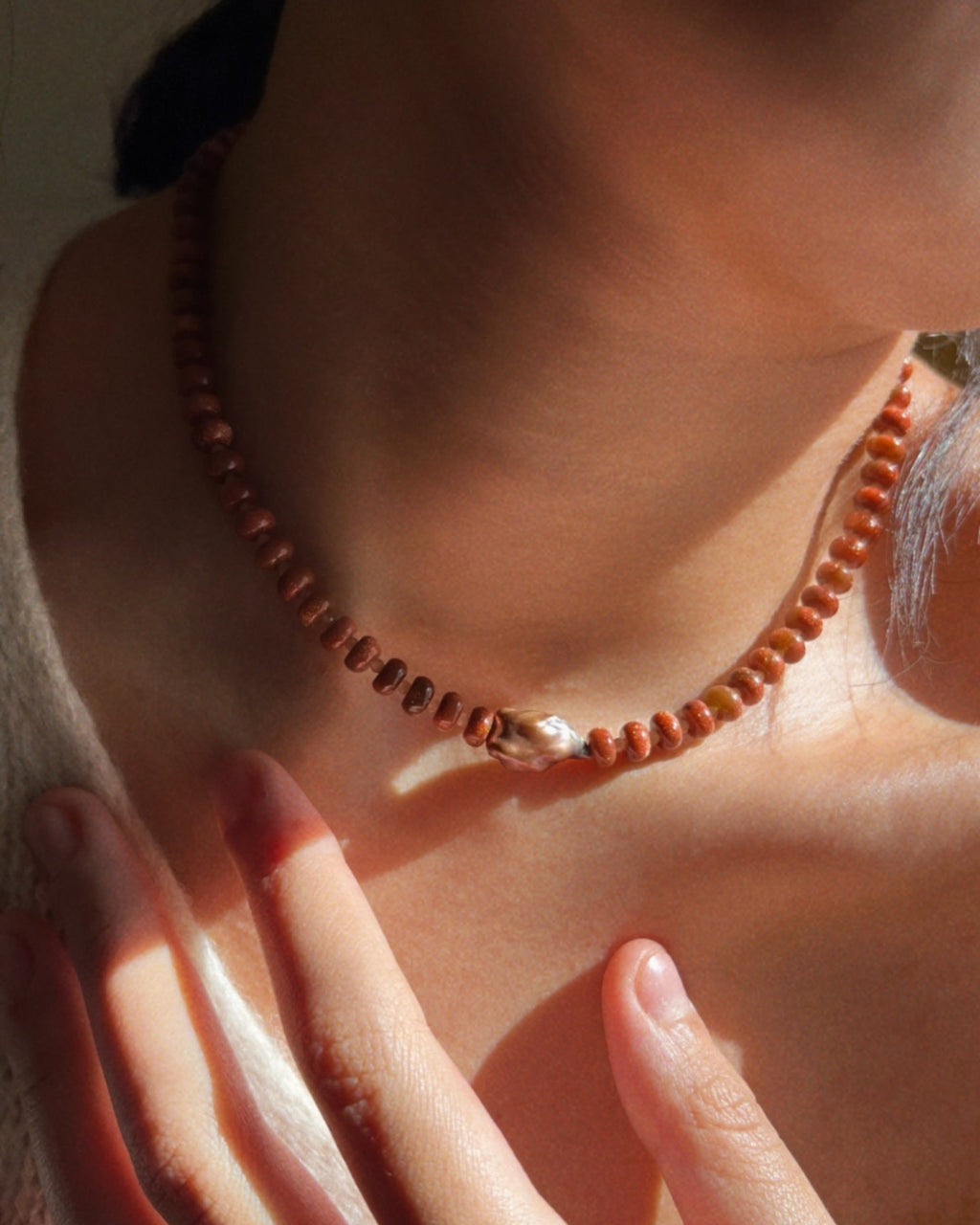 Close-up shot of a brown beaded necklace with a centered brown natural pearl