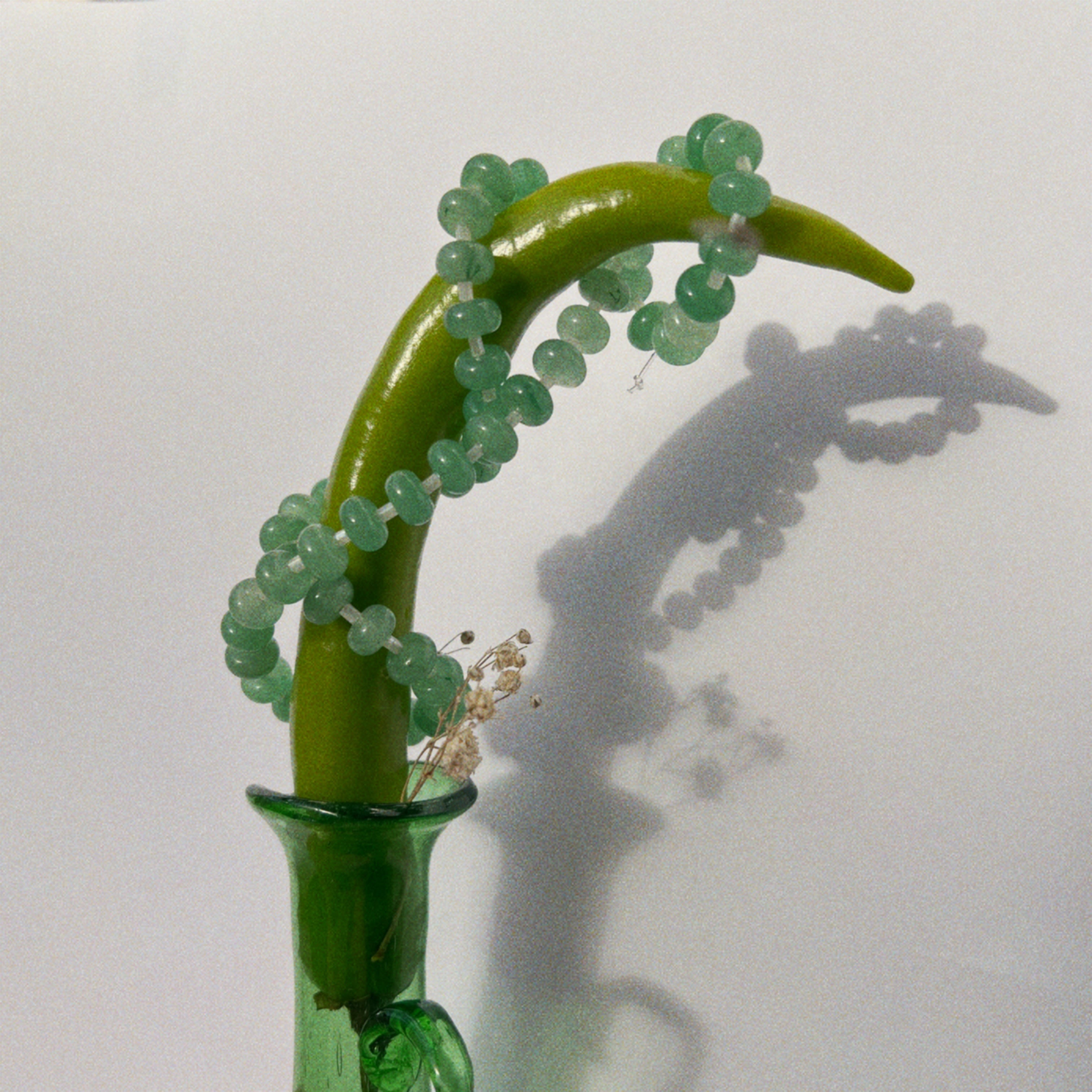 clode-up shot of a handmade necklace made using button shaped beads of green agate stones with tiny white cream glass beads. trending chunky beaded necklace for summer - white cream and green color combo